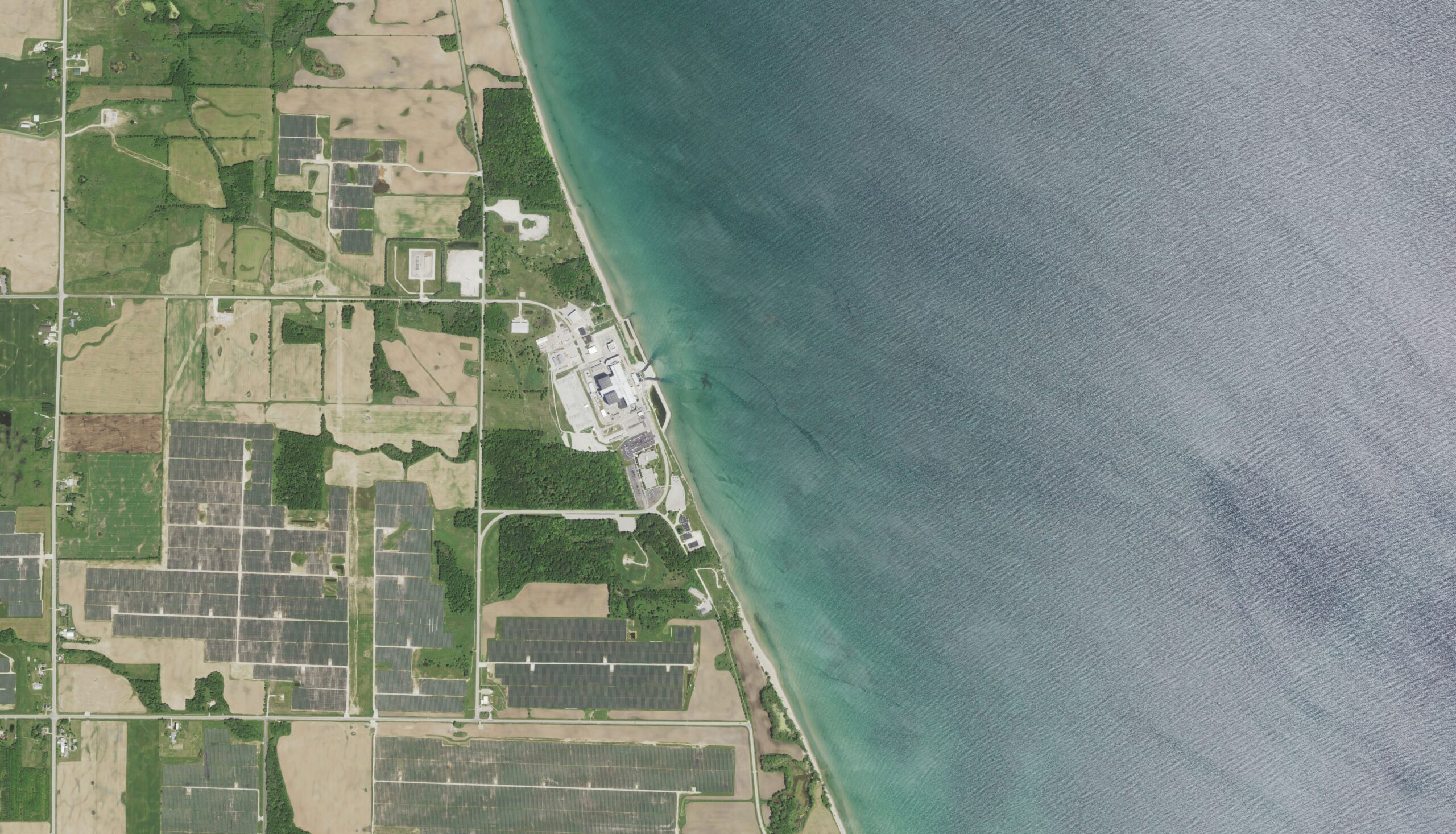 aerial view of Wisconsin farmland, seen in green and tan squares, with the blue shore of Lake Michigan visible on the left side of the image.